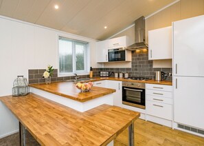 A modern kitchen with white cabinets, a wooden countertop, a gas stove, and a built-in oven.