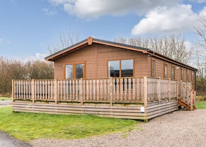 Une cabane en bois avec un balcon, une allée en gravier et une zone herbeuse.
