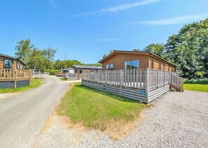 A row of wooden mobile homes with a gravel driveway and a wooden fence.