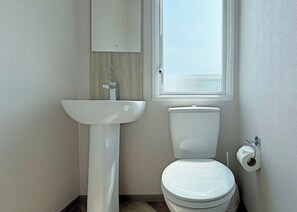 A bathroom with a white sink, toilet, and window.