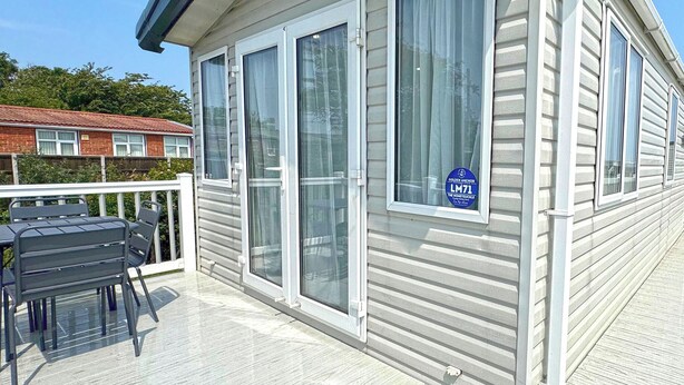 Un bâtiment d’un seul étage doté d’un espace extérieur couvert, d’une terrasse avec une table et des chaises, et d’une enseigne indiquant qu’il s’agit d’un établissement affilié à Golden Anchor.