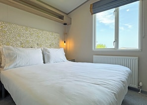 Ein Schlafzimmer mit Bett, einem an der Wand befestigten, mosaikverzierten Kopfteil, einem Fenster mit Blick und einer Heizung.