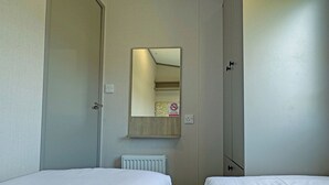 Une chambre d’hôtel avec deux lits, un miroir, un radiateur et une porte.