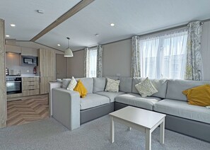 A modern living room with a sectional sofa, a small table, and a kitchen area in the background.