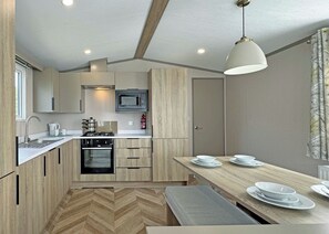 A compact kitchen with a microwave, stove, sink, and wooden cabinets.