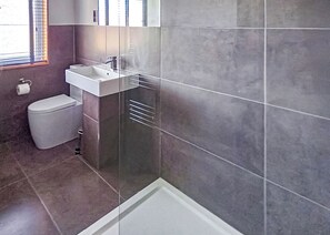 A modern bathroom with a shower, toilet, and sink.