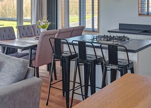 A modern kitchen with a gas stove, bar stools, and a dining table.