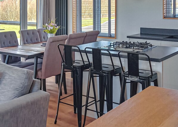 Une cuisine moderne équipée d’une cuisinière à gaz, de tabourets de bar et d’une table à manger.