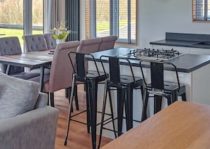 A modern kitchen with a gas stove, bar stools, and a dining table.
