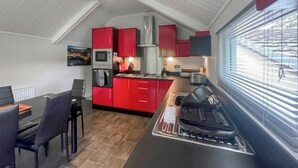 A compact kitchen with red cabinets, a microwave, and a gas stove. - 3 bedroom accommodation in Milnthorpe (Milnthorpe)