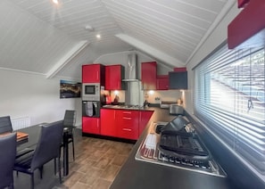 A compact kitchen with red cabinets, a microwave, and a gas stove.