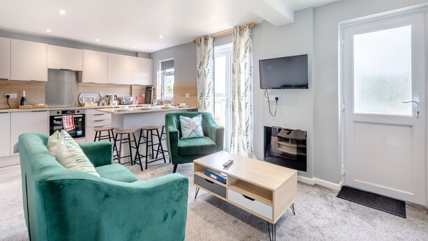 A modern living room with a sofa, coffee table, and a TV mounted on the wall.