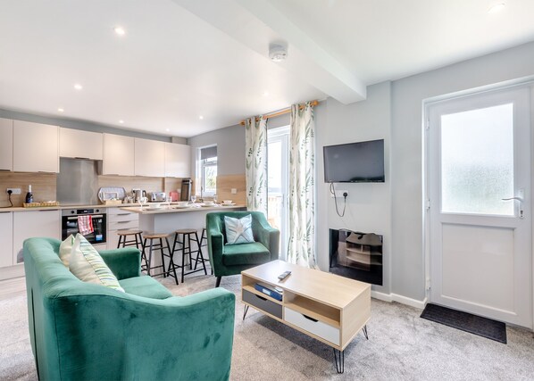 A modern living room with a sofa, coffee table, and a TV mounted on the wall.