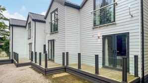A modern two-story house with a covered porch, large windows, and a gravel driveway. - 3 bedroom accommodation in Milnthorpe (Milnthorpe)
