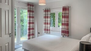 A bedroom with a bed, a bedside table, a lamp, and a view of the outdoors through a window. - 3 bedroom accommodation in Milnthorpe (Milnthorpe)