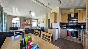 Un salon avec un canapé, une table à manger avec des chaises, une cuisine avec des meubles en bois et un réfrigérateur.