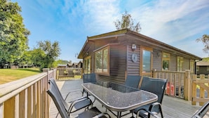 Une cabane en bois dotée d’une terrasse, de meubles de jardin et offrant une vue sur les environs.