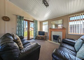 Una sala de estar con dos sofás de cuero, un televisor, una chimenea y un ventanal corredero que da a un patio.