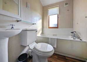 A bathroom with a toilet, sink, and bathtub. - 1 bedroom accommodation in Carnforth (Carnforth)