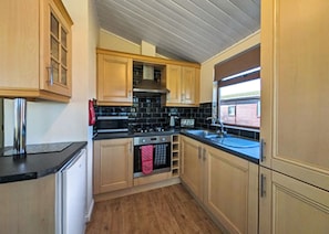 A compact kitchen with wooden cabinets, a stove, and a sink.
