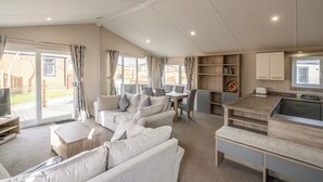 A spacious living area with a sofa set, a dining table, and a kitchen area.