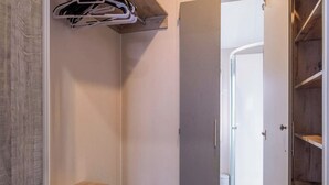A walk-in closet with a wooden bench, a hanging rack, and a glass shower door.