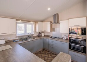 A compact kitchen with a gas stove, oven, and a window with blinds.