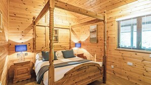 A four-poster bed in a log cabin room with a window and a nightstand with a lamp. - 1 bedroom accommodation in Harrogate (Harrogate)