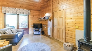A log cabin interior with a sofa, television, fireplace, and wooden walls. - 1 bedroom accommodation in Harrogate (Harrogate)