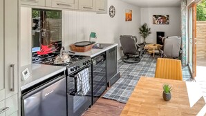 A modern kitchen with stainless steel appliances, a dining area with a wooden table, and a view of the outdoors.