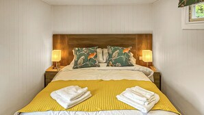A hotel room with a bed, two nightstands, two lamps, and a window.
