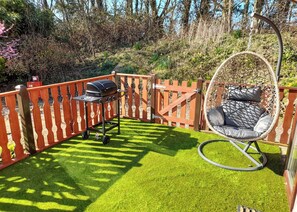 A patio with a grill, a hanging chair, and a wooden fence. - 3 bedroom accommodation in Carnforth (Carnforth)