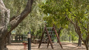 Une aire de jeux équipée d’une balançoire, d’une structure d’escalade et d’une zone délimitée par une clôture.