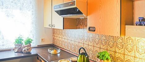 A kitchen with wooden cabinets, patterned backsplash, and a stove with a kettle.