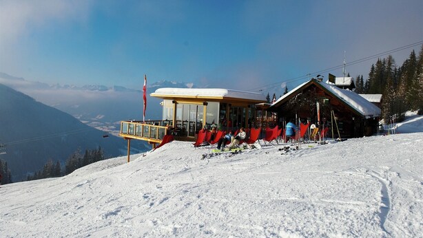 A mountain lodge with a glass-enclosed dining area and red chairs.