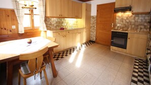 A kitchen with wooden cabinets, a checkered floor, a dining table with chairs, and a stove.