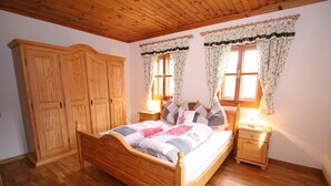 A bedroom with a wooden bed, two nightstands, a wardrobe, and floral curtains.