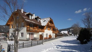 A traditional wooden chalet with a balcony, a snow-covered driveway, and a clear blue sky. - Chalet in Lungau near Ski Slopes (Sankt Margarethen im Lungau)