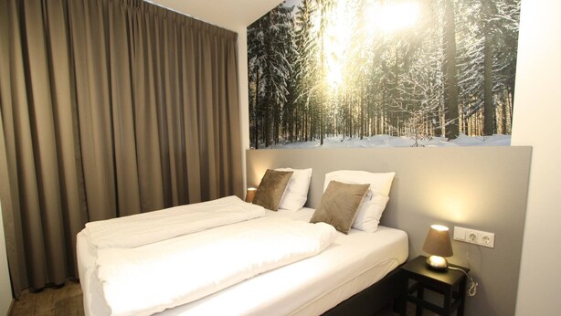 A hotel room with a large bed, a nightstand with a lamp, and a forest-themed wall mural. - Chalet in Lungau near Ski Slopes (Sankt Margarethen im Lungau)