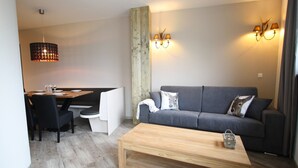 A modern living room with a wooden coffee table, a grey sofa, and a dining area with a wooden table and chairs. - Chalet in Lungau near Ski Slopes (Sankt Margarethen im Lungau)