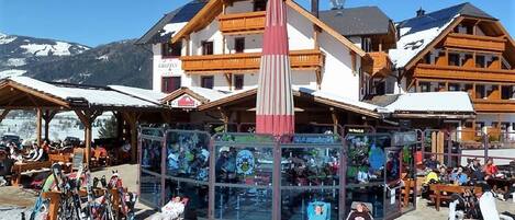 Un centro de esquí con edificios de madera, un telesilla y una estructura de vidrio con gente en su interior.