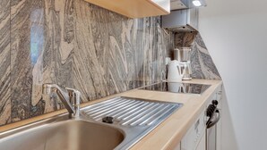 A modern kitchen with a marble backsplash, stainless steel sink, and a coffee maker.