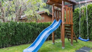 A wooden playground structure with a blue slide and swings.