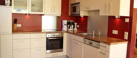 A compact kitchen with white cabinets, a built-in oven, a microwave, and a coffee maker.