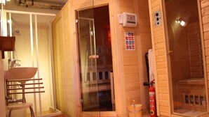 Un sauna doté d’une porte en verre, d’un banc en bois, d’un porte-serviettes, d’un extincteur et d’une petite table en bois.