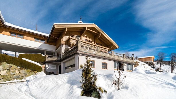 A chalet-style building with a sloped roof and a balcony, surrounded by snow. - Apartment in Hollersbach near Kitzbühel ski lift (Hollersbach im Pinzgau)