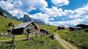 Un village de montagne isolé, avec ses maisons traditionnelles en bois, un ciel dégagé et un paysage montagneux en toile de fond.