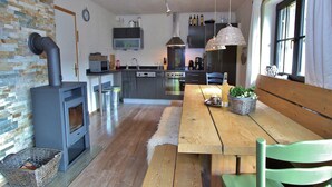 Una cucina moderna con un camino a legna, un tavolo da pranzo con sedie e una panca.