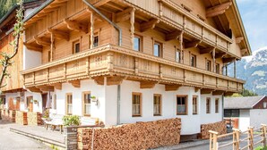 Ein traditionelles Holzchalet mit mehreren Balkonen, einem Steinfundament und Blick auf die umliegenden Berge.