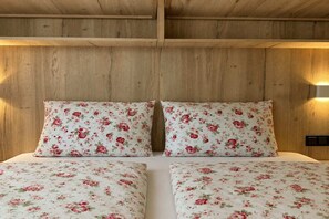 Una cama con ropa de cama estampada con flores y cabecera de madera.